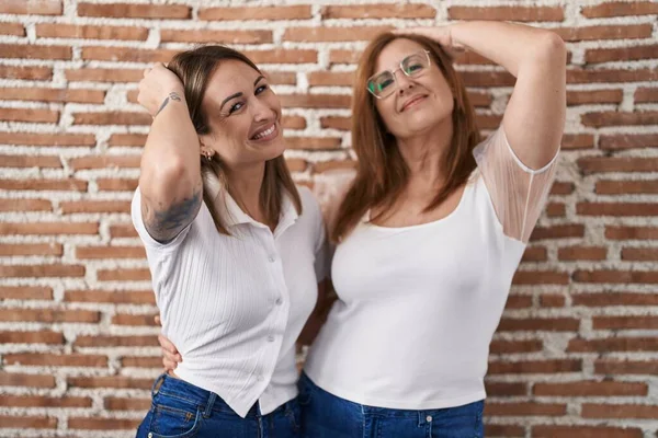 西班牙裔母亲和女儿穿着休闲的白色T恤 自信地微笑着 手举着手抚摸着头发 显得迷人而时尚 — 图库照片