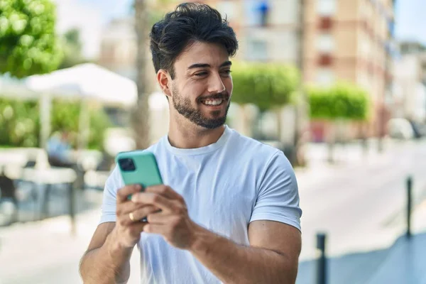 Jonge Spaanse Man Glimlacht Vol Vertrouwen Met Behulp Van Smartphone — Stockfoto