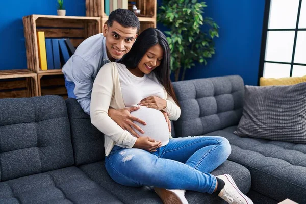 Young Latin Couple Expecting Baby Hugging Each Other Sitting Sofa — Photo