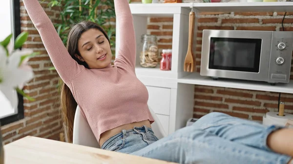 stock image Young beautiful hispanic woman relaxed with hands on head sitting on table at dinning room