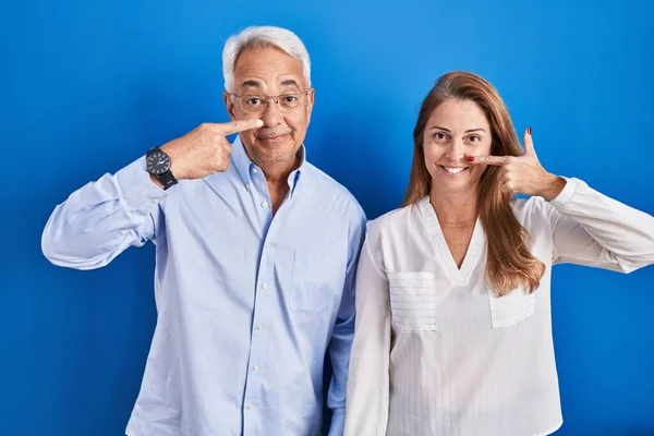 Orta Yaşlı Spanyol Bir Çift Mavi Arka Planda Durup Parmaklarını — Stok fotoğraf