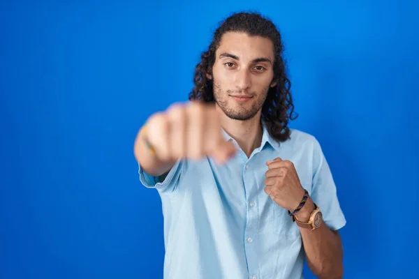 青の背景に立っている若いヒスパニック系の男が戦うために拳をパンチ 積極的かつ怒りの攻撃 脅威と暴力 — ストック写真