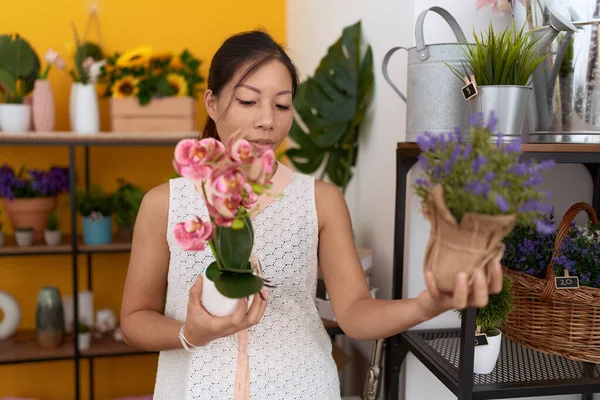 年轻的亚洲女花匠在花店拿着植物 — 图库照片