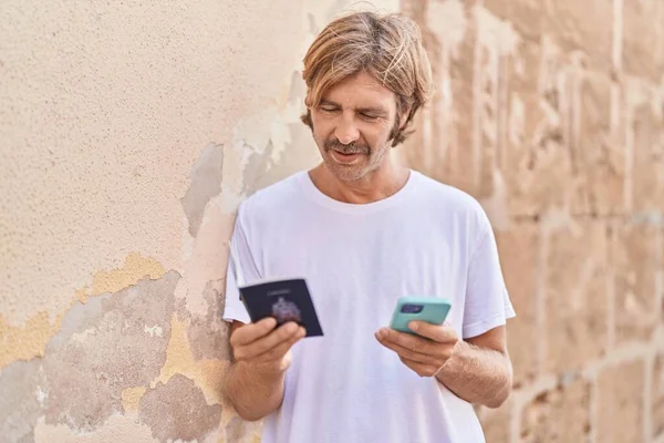 Young Blond Man Using Smartphone Holding Passport Street — Stok fotoğraf