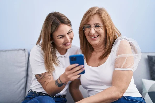집에서 소파에 스마트폰을 사용하는 어머니와 — 스톡 사진