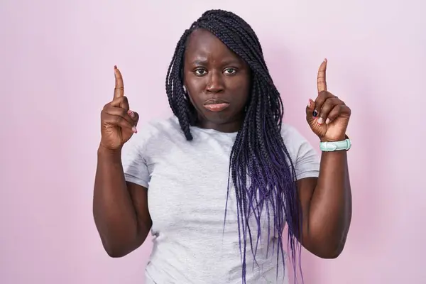 Jonge Afrikaanse Vrouw Staat Roze Achtergrond Wijzen Omhoog Kijken Verdrietig — Stockfoto