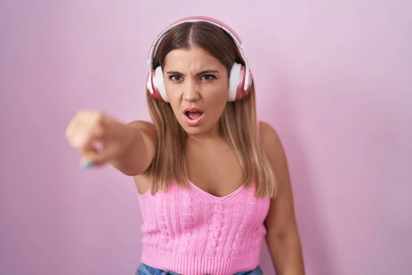 Mladá Blondýnka Která Poslouchá Hudbu Pomocí Sluchátek Ukazujících Prstem Překvapeně — Stock fotografie
