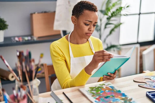 African American Woman Artist Reading Book Serious Expression Art Studio — Stock Photo, Image