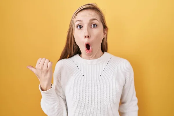 Young Caucasian Woman Wearing White Sweater Yellow Background Surprised Pointing — Stock Photo, Image