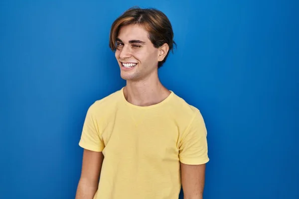 Mladý Muž Stojící Nad Modrým Pozadím Mrkající Kameru Sexy Výrazem — Stock fotografie