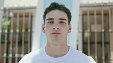 Sokakta ciddi bir ifadeyle duran İspanyol genç adam.