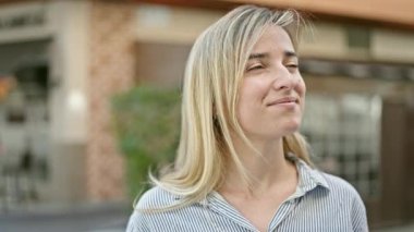 Kahvecinin terasında kendinden emin gülümseyen genç sarışın kadın.