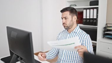 Genç İspanyol iş adamı ofiste el hayranı olarak belgeyi kullanarak terliyor.