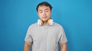 İzole edilmiş mavi arka planda gülümseyen müzik dinlemek.