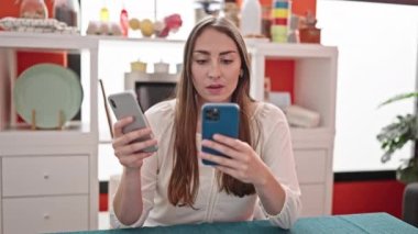 Yemek odasındaki masada oturan akıllı telefonları kullanan genç ve güzel İspanyol kadın.