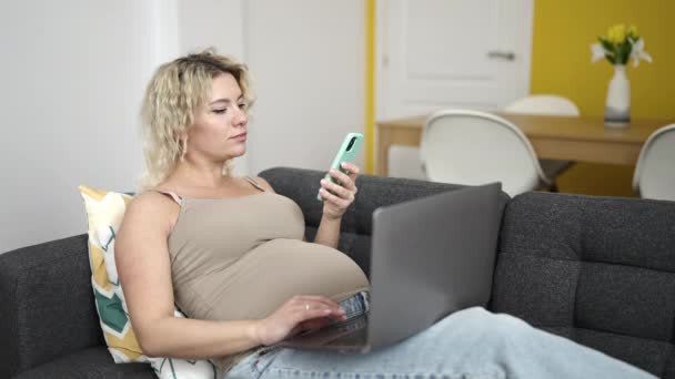 Akıllı Telefon Dizüstü Bilgisayar Kullanan Hamile Bir Kadın Evdeki Kanepede — Stok video