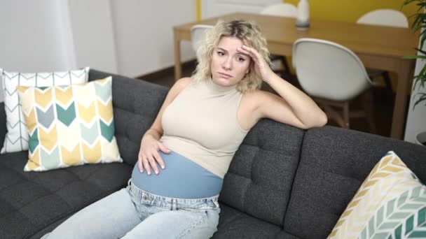 Jonge Zwangere Vrouw Zittend Bank Met Gestreste Uitdrukking Aanraken Buik — Stockvideo