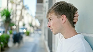 Sokakta ciddi bir ifadeyle yan tarafa bakan beyaz bir genç.