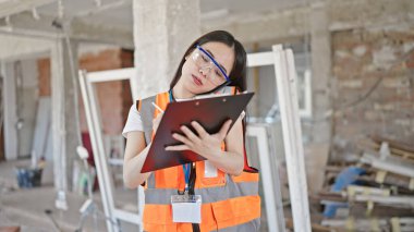 İnşaat raporu yazan Çinli genç bir müteahhit inşaat alanında akıllı telefondan konuşuyor.