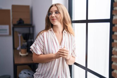 Genç sarışın iş kadını ofiste kendinden emin duruyor.