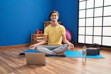 Young caucasian man smiling confident having online yoga class at sport center