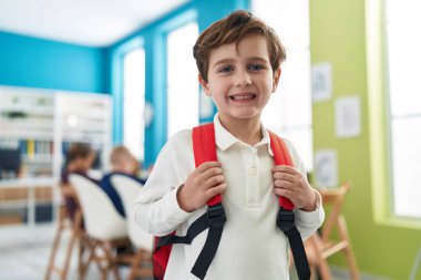 Sınıfta kendine güvenen sevimli beyaz çocuk gülümsüyor.