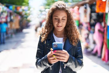 Sokak pazarında akıllı telefon kullanan, kendine güvenen, güzel İspanyol bir kadın.