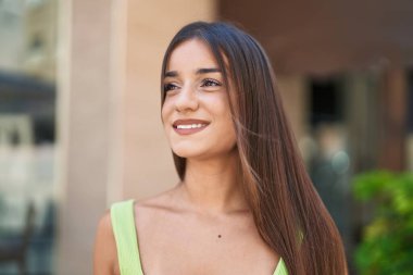 Young beautiful hispanic woman smiling confident looking to the side at street