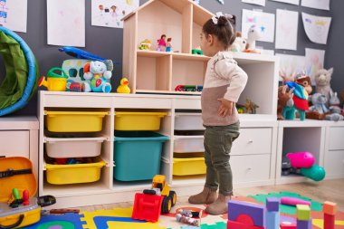 Adorable hispanic girl standing on back view at kindergarten