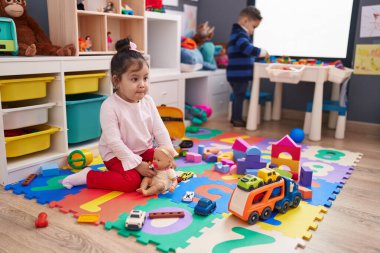 Sevimli bir çocuk ve kız yerde oturup anaokulunda oynuyorlar.