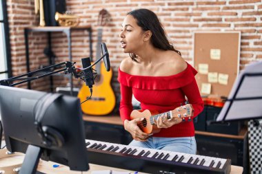 Genç Afrikalı Amerikalı kadın müzisyen müzik stüdyosunda ukelele çalıyor.