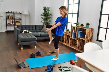 Young caucasian woman smiling confident stretching leg at home