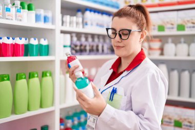 Young beautiful plus size woman pharmacist holding medication bottles at pharmacy