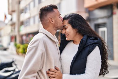 Man and woman couple hugging each other and kissing at street