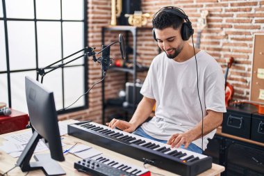 Genç Arap müzisyen müzik stüdyosunda piyano klavyesi çalıyor.