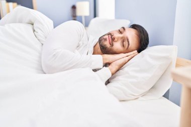 Genç İspanyol adam yatakta uzanıp yatak odasında uyuyor.