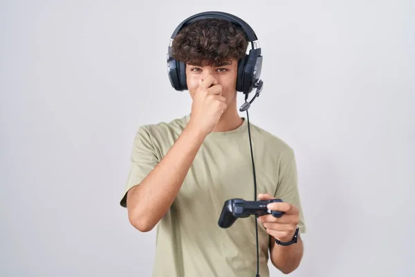Hispanic Teenager Playing Video Game Holding Controller Smelling Something Stinky — Stock Photo, Image