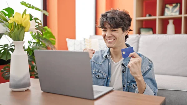 stock image Young hispanic man shopping with laptop and credit card with winner expression at home