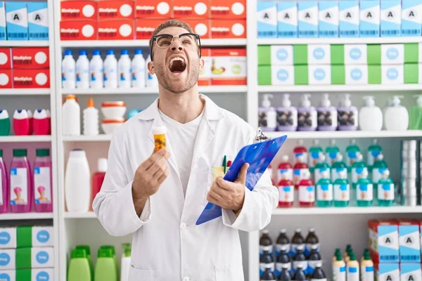 Young Caucasian Man Working Pharmacy Drugstore Holding Pills Angry Mad — Stock Photo, Image
