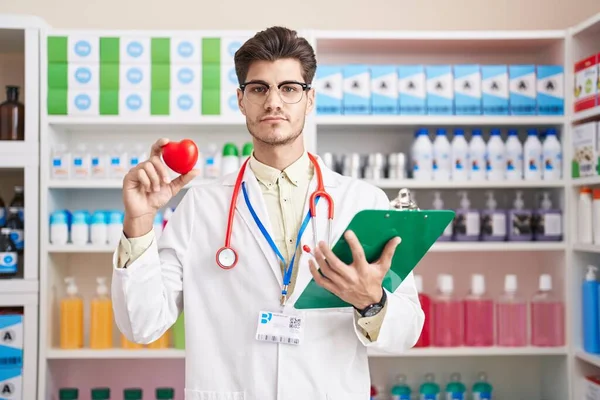 Homem Hispânico Jovem Trabalhando Farmácia Farmácia Segurando Coração Relaxado Com — Fotografia de Stock