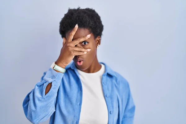 Africano Americano Mulher Sobre Fundo Azul Espreitando Choque Cobrindo Rosto — Fotografia de Stock