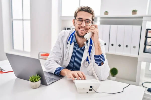 Młody Lekarz Korzystający Laptopa Rozmawiający Przez Telefon Klinice — Zdjęcie stockowe
