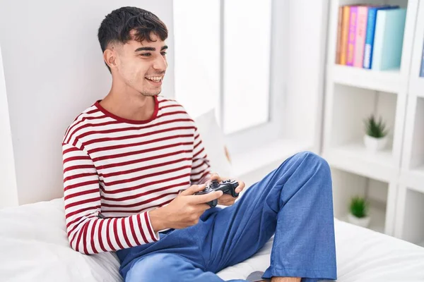 年轻的惊慌失措的男人坐在床上玩电子游戏 — 图库照片