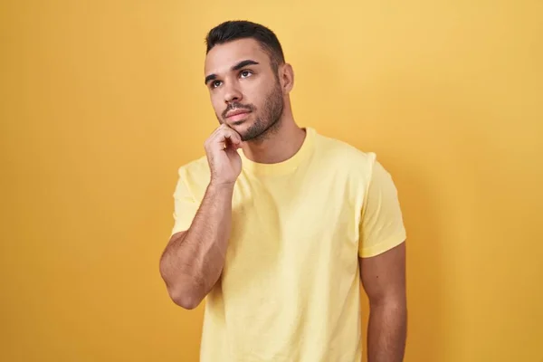Homem Hispânico Jovem Sobre Fundo Amarelo Com Mão Queixo Pensando — Fotografia de Stock