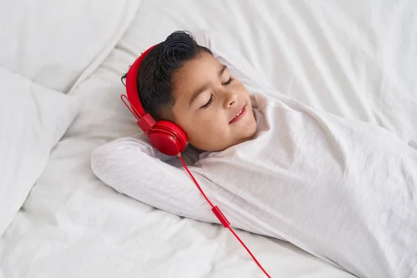 他那可爱的惊慌失措的儿子躺在床上听音乐 — 图库照片