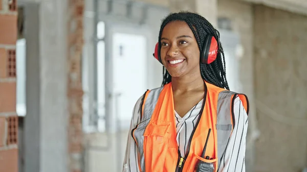 Mujer Afroamericana Constructora Sonriendo Confiada Usando Auriculares Con Los Brazos —  Fotos de Stock