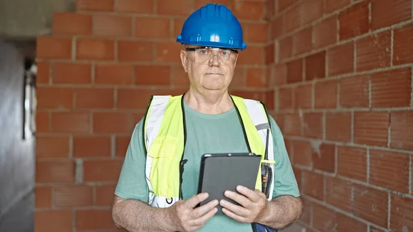 Medelålders Gråhårig Man Byggmästare Håller Touchpad Med Avslappnad Uttryck Byggarbetsplatsen — Stockfoto