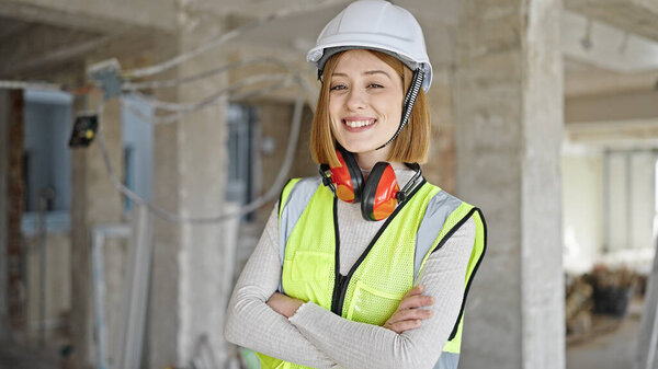 Young blonde woman architect smiling confident standing with arms crossed gesture at construction site
