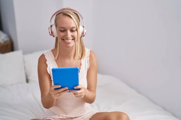 Young Blonde Woman Using Touchpad Headphones Sitting Bed Bedroom — Stok fotoğraf