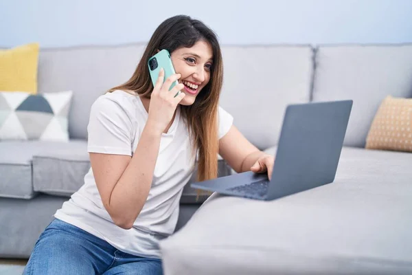Genç Spanyol Kadın Dizüstü Bilgisayar Kullanıyor Evde Akıllı Telefondan Konuşuyor — Stok fotoğraf